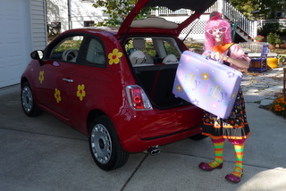 Silly Jilly the Clown loads up her red Fiat 500 with her magic suitcase. 